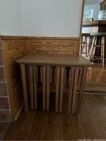 Full view of the nesting tables set with all four tables stacked together under the largest table, showing the caster wheels on the largest table.
