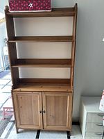 Front view of the full shelving unit with three open shelves and double-door cabinet below.