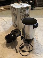 West Bend 12 to 30 Cup Party Percolator with lid, power cord, and original box on beige fabric surface.