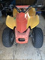 Front view showing yellow and orange plastic body, single headlight opening, front tires and fenders.