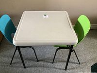 Top and side view of white children's table with green and blue chairs set up side by side.