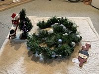 Top-down photo showing green garland with silver and white baubles, wooden snowman face door hanger, and part of snowmen-tree figurine decoration