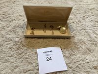 Five pairs of clip on earrings in Eaton brand case on a beige carpet background with lot card visible.