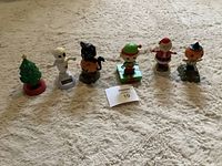 Photo showing seven festive solar dancing figurines arranged in a row on carpet, including Christmas tree, mummy, cat pumpkin, elf, Santa, and pumpkin witch.