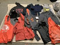 Full view of all 10 kid's hoodies and sweatshirts laid out on a beige background showing various colors and logos.