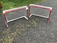 Two mini hockey nets placed on grass with visible red and white frame and mesh netting