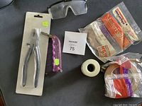 Photo showing stained glass pliers in packaging, purple-handled glass cutter, safety glasses, and rolls of foil tape including VenturTape.