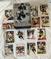 Front view of 14 Sidney Crosby hockey cards spread out with O-Pee-Chee 2009-10 Hockey metal tin in center showing Crosby in Penguins uniform.
