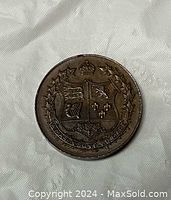 Reverse side of the 1927 Canadian Confederation coin featuring a crowned shield divided into four sections surrounded by maple leaves and Latin motto.