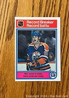 Front side of 1982-83 O-Pee-Chee Wayne Gretzky hockey card showing image of Gretzky in Oilers uniform with NHL Record Breaker label.