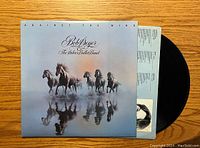 Front album cover with horses running through water artwork and vinyl record partially visible inside.