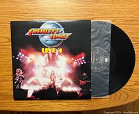 Front cover of Frehley's Comet Live + 1 vinyl showing band performing live with bright stage lights.