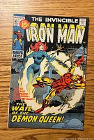Front cover of The Invincible Iron Man #42 comic showing Iron Man fighting the Demon Queen with vibrant colors and text.