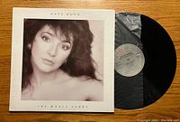 Front of vinyl album cover showing Kate Bush monochrome portrait with text 'The Whole Story'. Record partially out of gray inner sleeve.