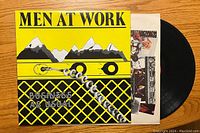 Front cover of Men at Work "Business as Usual" album with vinyl record and inner sleeve partially visible.