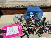 Lot displayed outside on table showing multiple assorted action figures and blue bin
