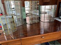 Group view of four brass and glass display cabinets on wooden surface