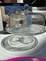 Glass pedestal cake stand with cover in natural light with original box in background