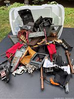 Image showing a large pile of loosely piled pirate ship themed Lego-like building blocks inside a clear plastic tub in grass background.