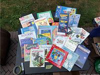 Top-down view of assorted colorful children's books spread out on a dark surface, showing various titles and covers clearly.