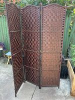 Front view of the wicker room divider showing three panels with a woven checkerboard pattern and arched tops.