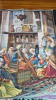 Large tapestry with indoor scene, multiple figures in period dress, intricate furnishings and architecture.