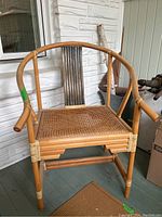 Full view of bamboo chair with caned seat and curved backrest featuring vertical slats