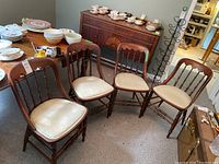 Four wooden dining chairs arranged side by side showing overall condition and design.