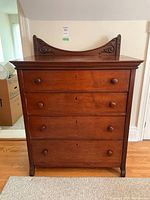 Front view of dresser showing four drawers and carved top backsplash