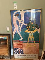 Full frontal view of gold-framed poster leaning against wall