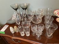 General overview of glassware collection including coupes, sherry glasses, aperitif glasses, martini glasses, and glass side plates on wooden dresser