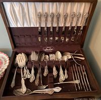 Wood box open showing fitted velvet and satin lined compartments with cutlery