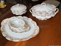 Photo showing the soup tureen with lid, serving platter, and covered serving dish on wooden table