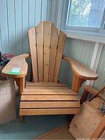 Front view of wooden Muskoka chair showing curved slatted back and wide armrests.