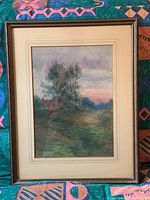 Full view of the framed watercolour painting on a multicolored patterned textile surface.