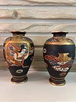 Front view of the pair of Japanese Satsuma vases showing the detailed hand-painted designs and gold accents