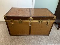 Front view of vintage McBrine Strongbox trunk showing the rectangular metal body, latch closures, and central lock.