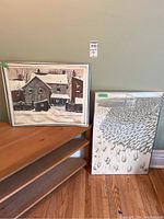 Photo showing two prints side by side on the floor against a wall; one is framed, the other unframed and buckled.