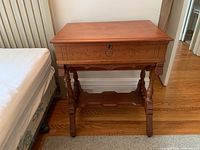 Front view of antique wooden writing desk showing hand-carved drawer and legs.