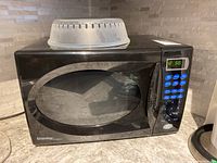 Black Danby Designer microwave oven on countertop with plastic turntable cover on top.