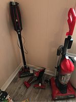 Three Dirt Devil vacuum cleaners in corner showing the upright, stick, and handheld units together.