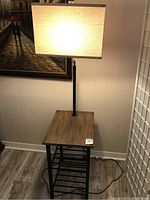 End table with built-in lamp fully assembled and lit, placed near a wall with floor showing.