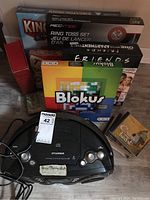 Photo showing the Sylvania radio/CD player at bottom center, surrounded by boxed games including Blokus, Rec-Tek ring toss set, King brand game, and Friends themed board game.