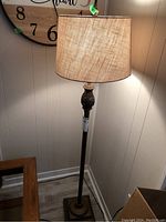 Full view of the floor lamp showing the base, stand, and illuminated fabric shade.