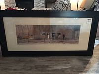 Frontal photo of the framed artwork, showing the entire piece with the black frame and matted light beige matting. The painting depicts five figures holding umbrellas on a rainy street.