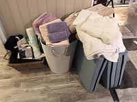 Photo of various towels, two baskets, and three blue-gray folding sleeping pads stacked