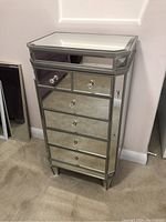 Front view of the mirrored jewelry cabinet showing all drawer fronts with clear jewel-like pulls.