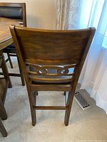 Back view of one wood chair showing decorative carved slat and dark finish