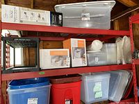 Shelf displaying a black over-the-door shoe rack, white small storage cabinets, various clear plastic bins, and bubble wrap rolls above.