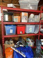 Front view of red storage shelving unit loaded with plastic bins and hardware